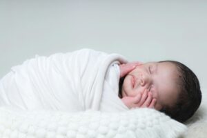 Adorable newborn baby peacefully sleeping wrapped in a white blanket, capturing innocence and tranquility.